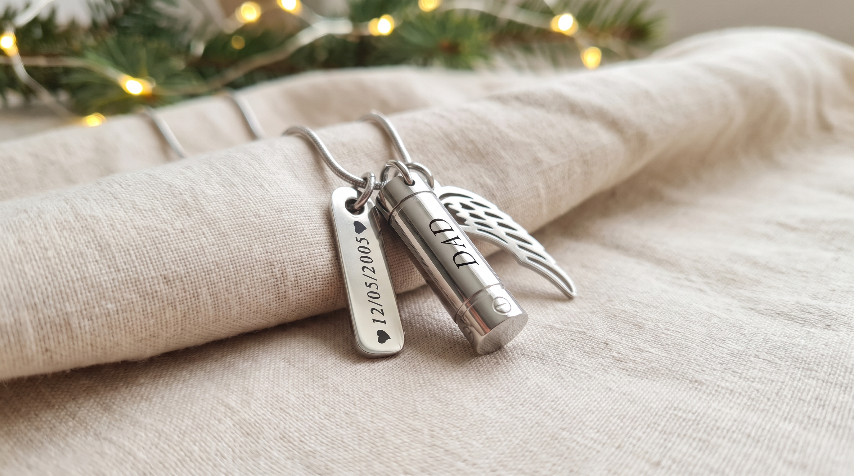 Silver memorial necklace engraved 'Nan' beside a lit candle and a handwritten recipe card at Christmas