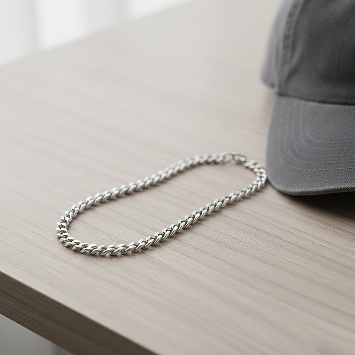 Silver curb chain necklace on the desk, waterproof non-tarnish unisex jewelry with warm elegant glow.