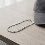 Silver curb chain necklace on the desk, waterproof non-tarnish unisex jewelry with warm elegant glow.