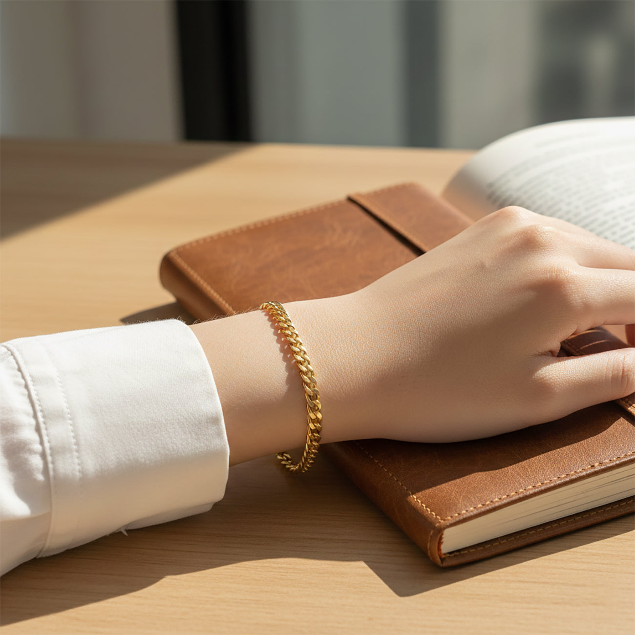 Close-up gold curb chain bracelet on woman, waterproof non-tarnish unisex jewelry with sleek modern finish.
