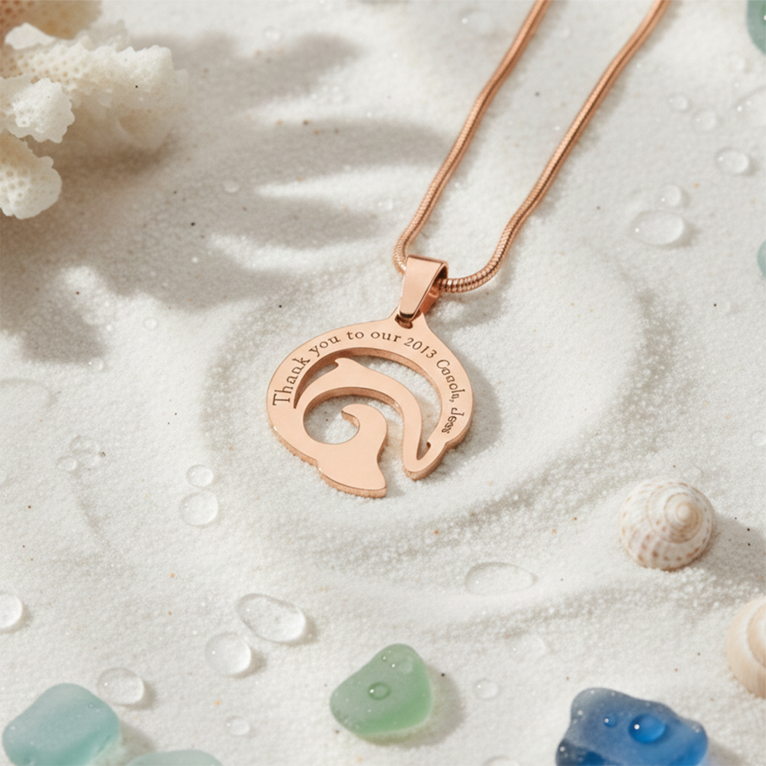 Rose gold dolphin necklace with engraved message on sandy background, belle fever resilience and empowerment pendant.
