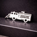 Belle Fever silver fire truck charm leaning on marble pedestal, personalised firefighter truck charm elegant jewellery gift