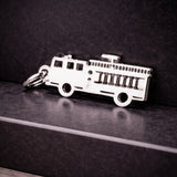 Belle Fever silver fire truck charm leaning on marble pedestal, personalised firefighter truck charm elegant jewellery gift