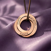 Interlinked Family Love Circles Necklace by Belle Fever — rose gold personalised rings engraved with family names, styled on soft fabric for a warm, sentimental feel.