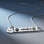 Personalized music bar necklace with engraved song code and heart charm displayed on a dark background, Belle Fever