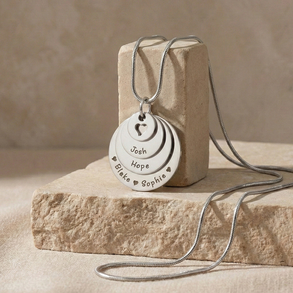 Belle Fever Tower of Love necklace with multiple engraved disc charms, styled on a natural stone surface