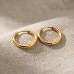 Gold chic sleeper hoop earrings with classic round hoop design displayed on neutral background