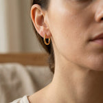 Woman wearing chic sleeper hoop earrings with small round hoop design