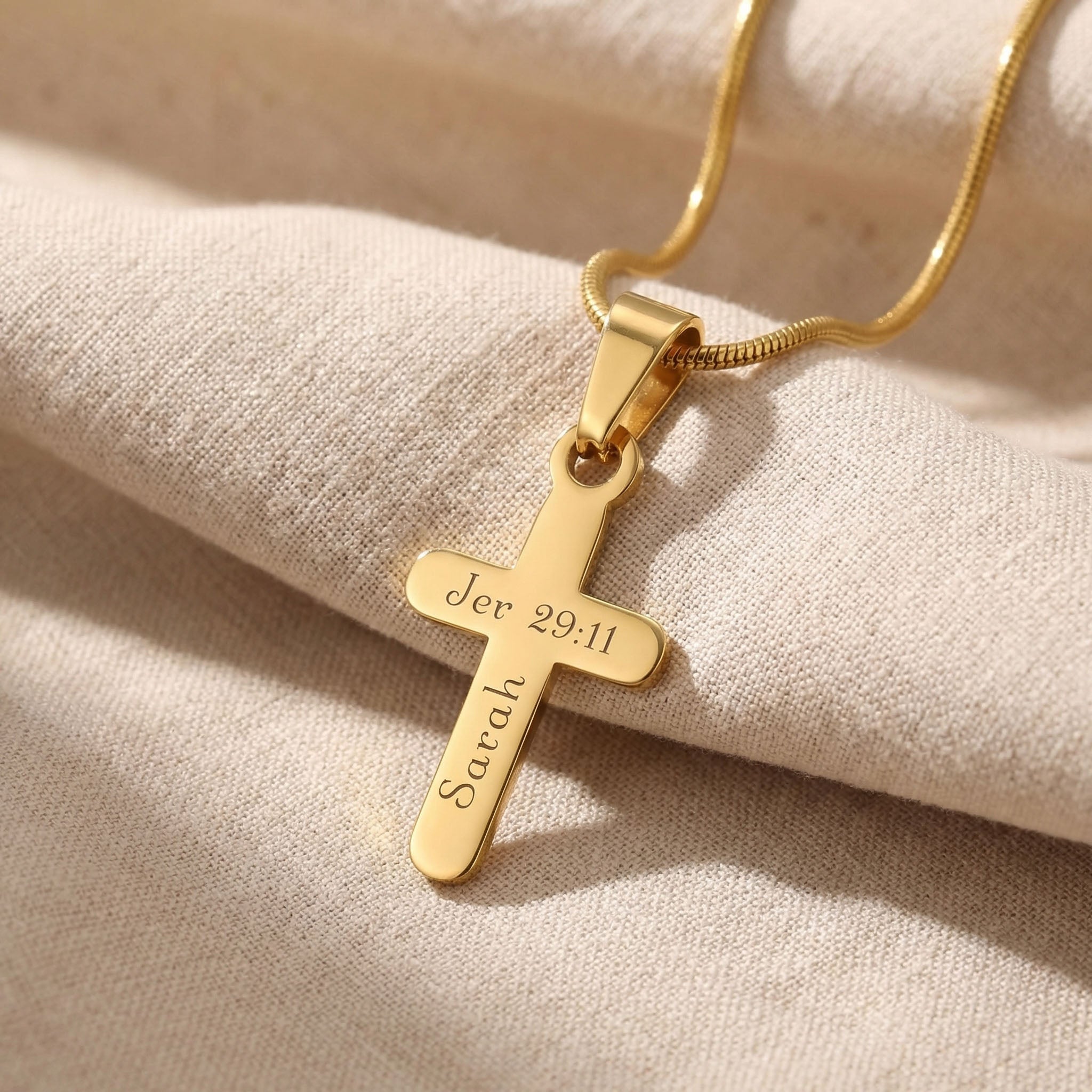 Gold cross name necklace with engraved name on cross pendant displayed on neutral background