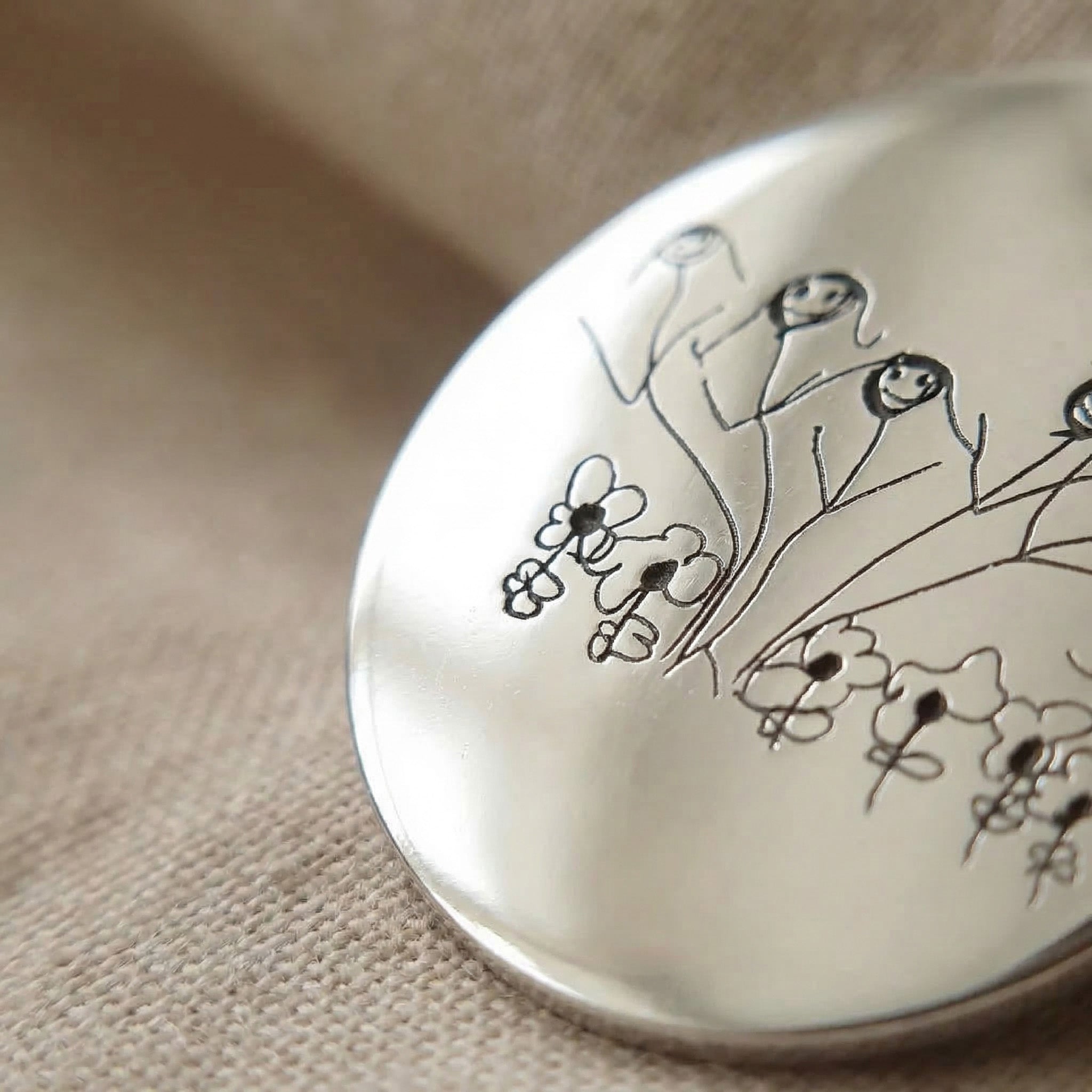 Close up of kids drawing necklace showing detailed engraved artwork on pendant