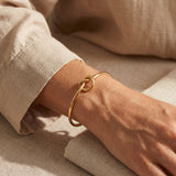Woman wearing knot bangle, minimalist symbolic bracelet representing love, connection and family bond