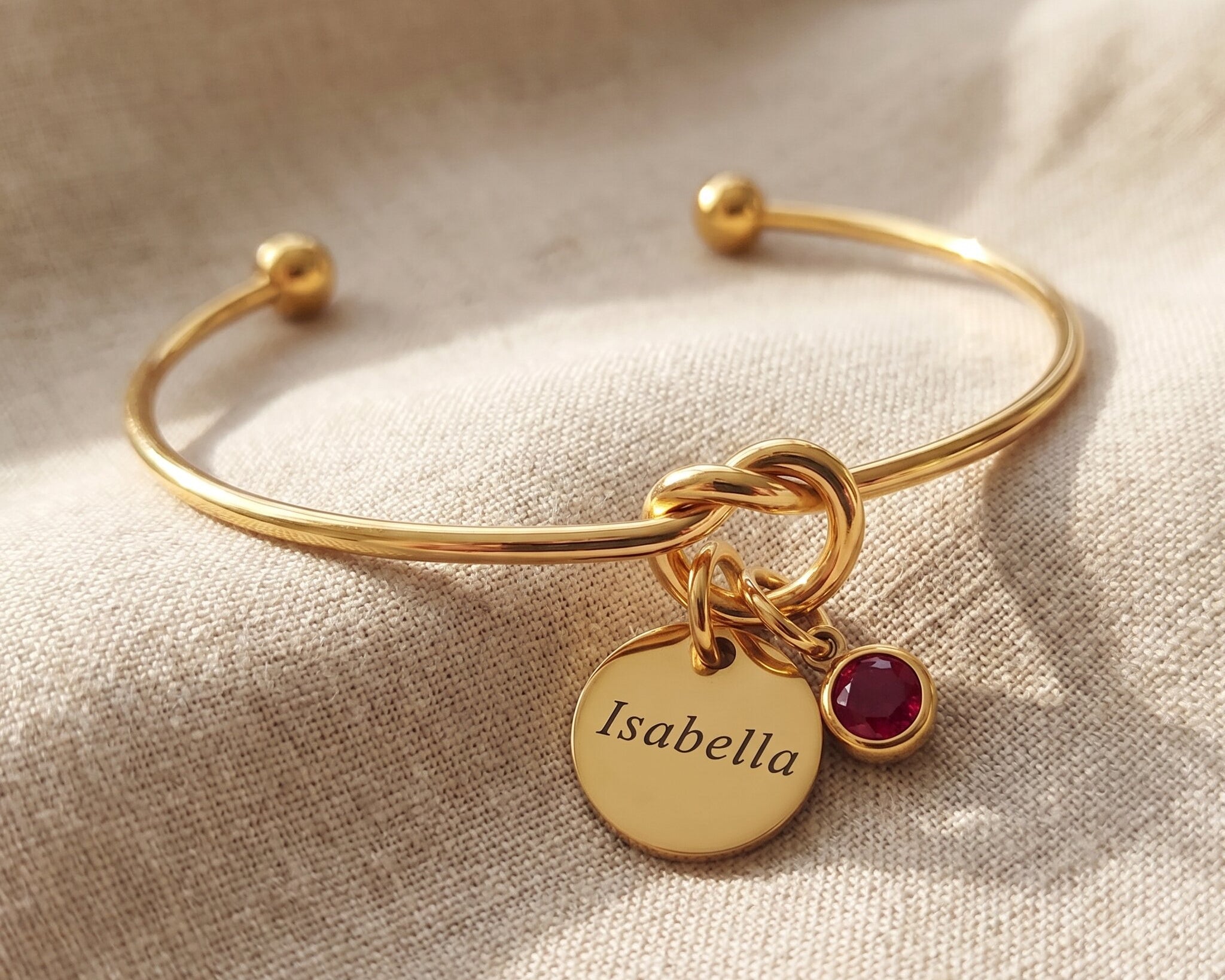 Knot bangle with personalised charm option, symbolic bracelet with engraved disc and birthstone detail