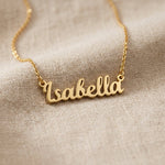 Gold personalised name necklace with script name pendant displayed on neutral background