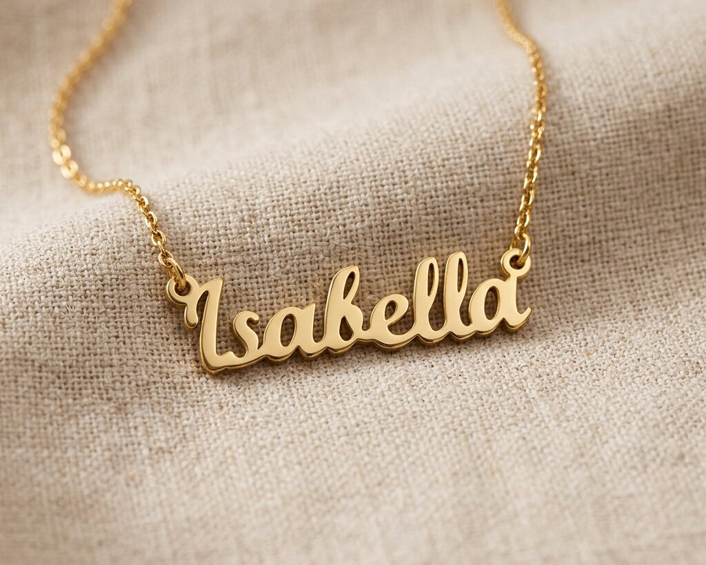 Gold personalised name necklace with script name pendant displayed on neutral background