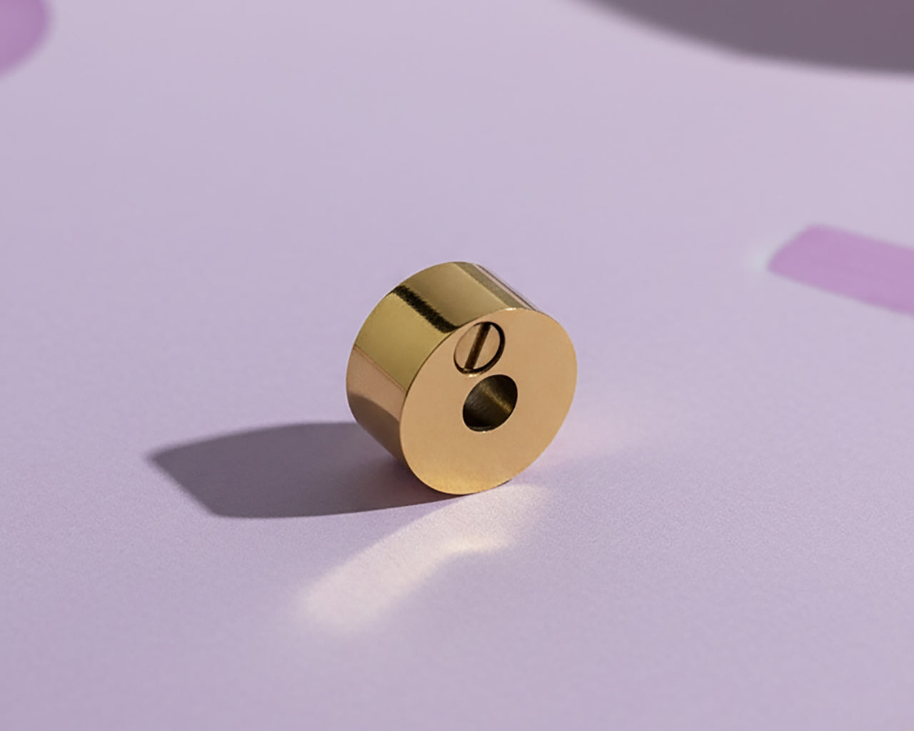 Belle Fever Round Cremation Charm – close-up of 15mm gold urn bead resting on soft lavender background, highlighting delicate craftsmanship. A heartfelt Belle Fever memorial bead symbolising eternal love and connection.