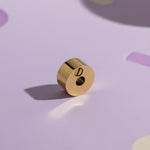 Belle Fever Round Cremation Charm – close-up of 15mm gold urn bead resting on soft lavender background, highlighting delicate craftsmanship. A heartfelt Belle Fever memorial bead symbolising eternal love and connection.
