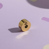 Belle Fever Round Cremation Charm – close-up of 15mm gold urn bead resting on soft lavender background, highlighting delicate craftsmanship. A heartfelt Belle Fever memorial bead symbolising eternal love and connection.
