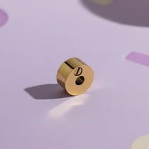 Belle Fever Round Cremation Charm – close-up of 15mm gold urn bead resting on soft lavender background, highlighting delicate craftsmanship. A heartfelt Belle Fever memorial bead symbolising eternal love and connection.