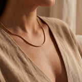 Woman wearing snake chain necklace, elegant minimalist chain jewellery for layering and modern styling