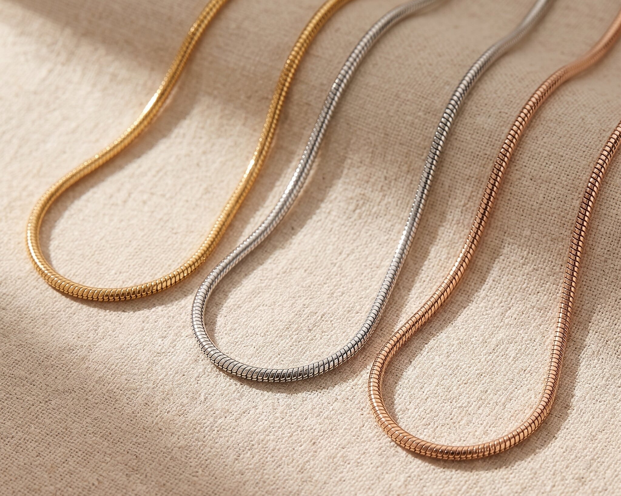 Snake chain necklace tone comparison showing gold, silver and rose gold minimalist chain finishes