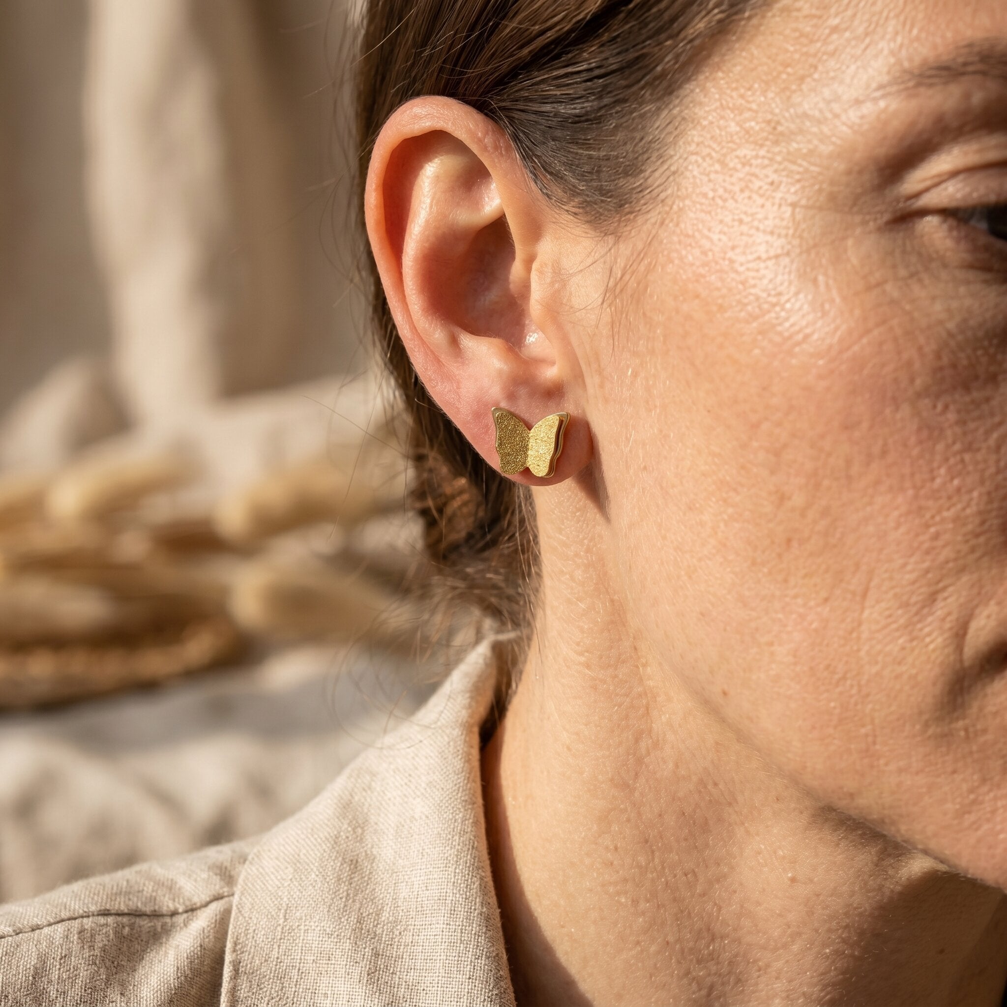 Woman wearing sparkling butterfly earrings, feminine jewellery symbolising transformation and beauty