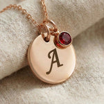 Close-up of Tokens of Love Necklace with initial charm and red birthstone detail