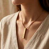 Woman wearing vertical bar necklace with engraved bar pendant on delicate chain
